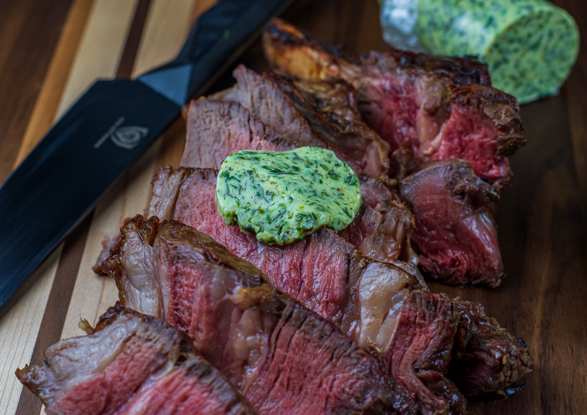 Garlic herb compound butter melting over a grilled ribeye steak