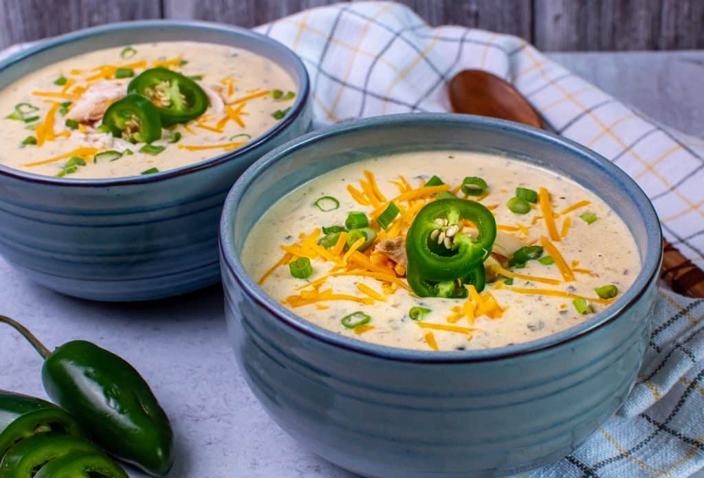 chicken jalapeno popper soup topped with shredded cheddar and sliced jalapeños