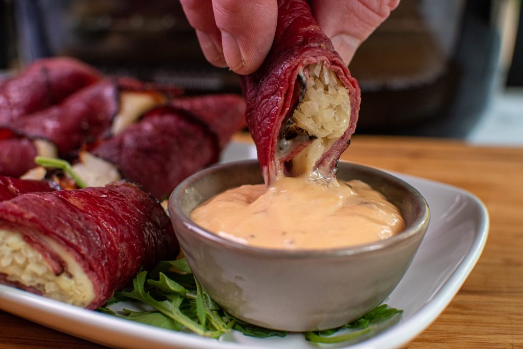dipping pastrami roll ups into Russian dressing