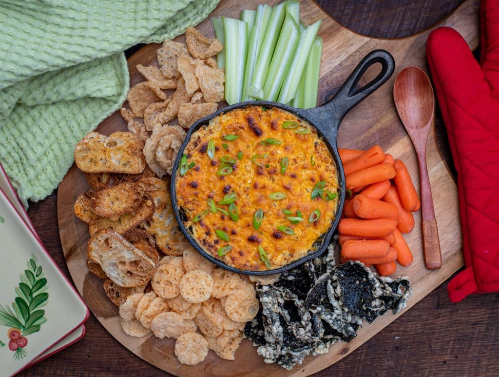 overhead view of crab dip with pork rinds, carrots, celery and crustinis