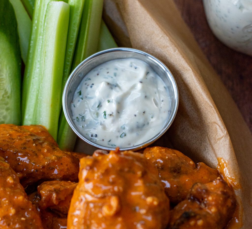 ramekin of ranch dressing served with carrots, celery, cucumbers and smoked buffalo wings
