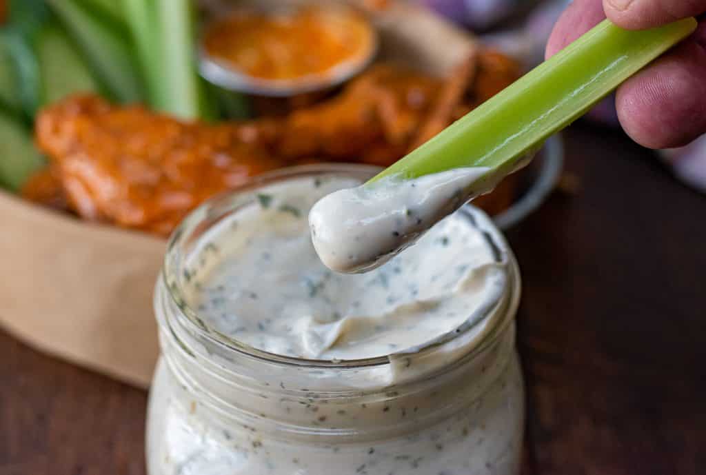 celery stick dipped in a mason jar of homemade ranch dressing
