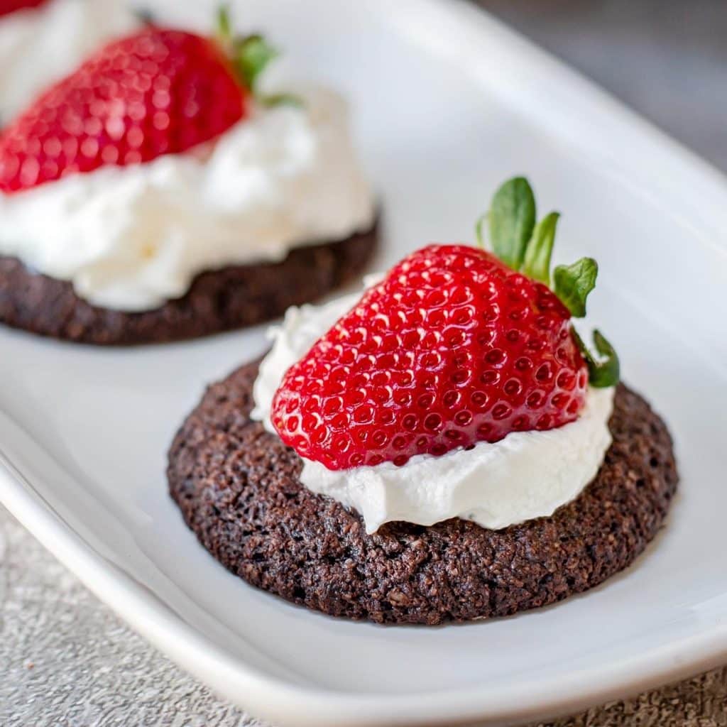 good dee's double chocolate chip cookie topped with whipped cream and strawberries