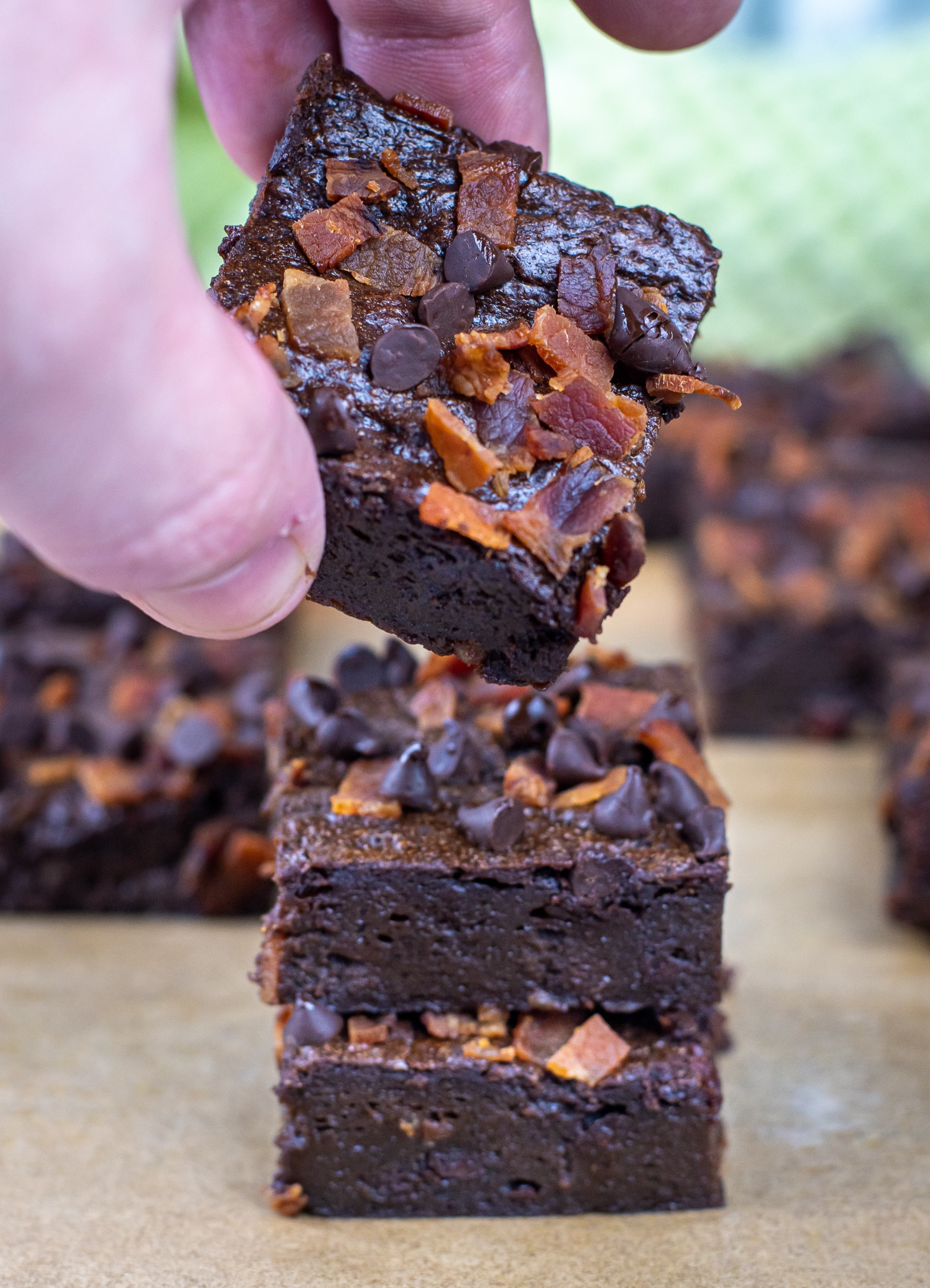 picking up a flourless keto brownie topped with bacon and chocolate chips