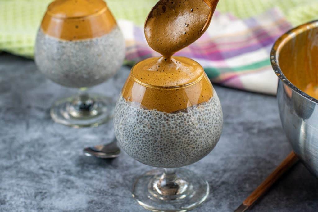 Spooning Dalgona coffee over chia seed pudding