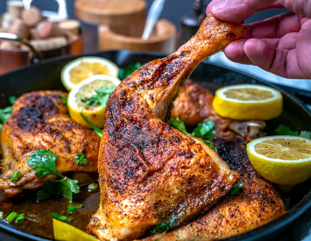 chicken leg quarter in a cast iron skillet with lemon pepper seasoning