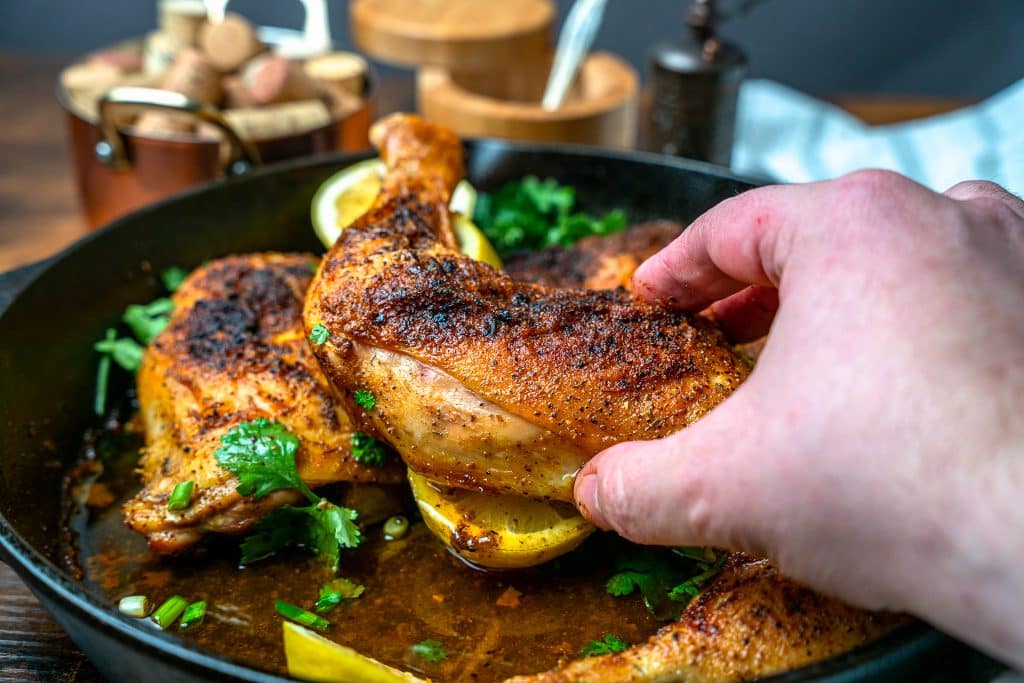 chicken leg quarter in a cast iron skillet with lemon pepper seasoning