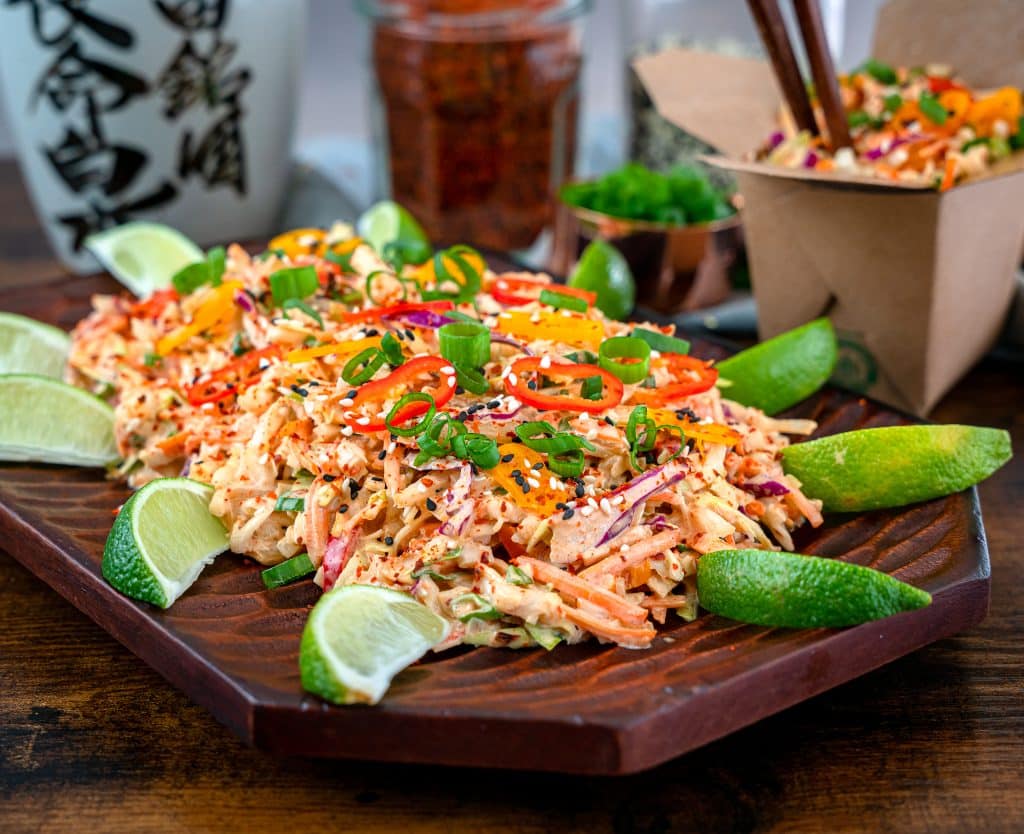kimchi coleslaw garnished with sesame seeds, chili flakes and lime wedges