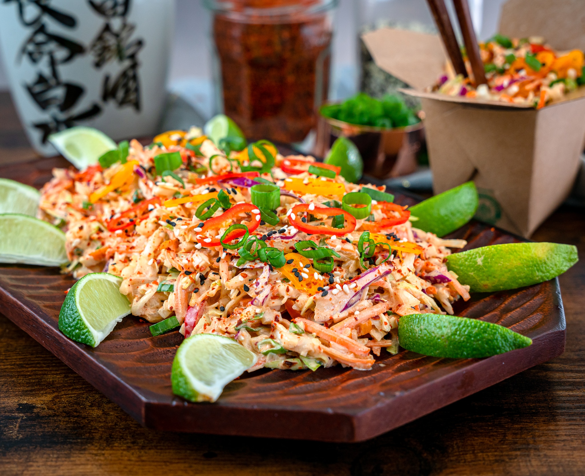 kimchi coleslaw garnished with sesame seeds, chili flakes and lime wedges