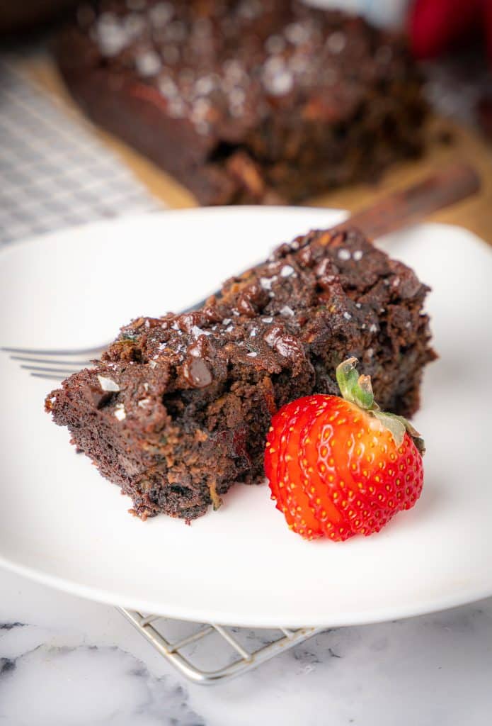 slice of chocolate pecan zucchini bread with a sliced strawberry