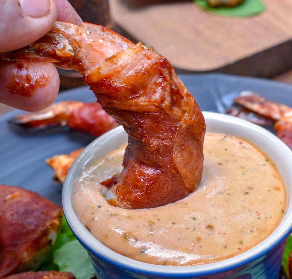 dipping a prosciutto wrapped shrimp into a spicy Calabrian chili aioli