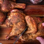cutting a smoked half chicken into quarters with a chef knife