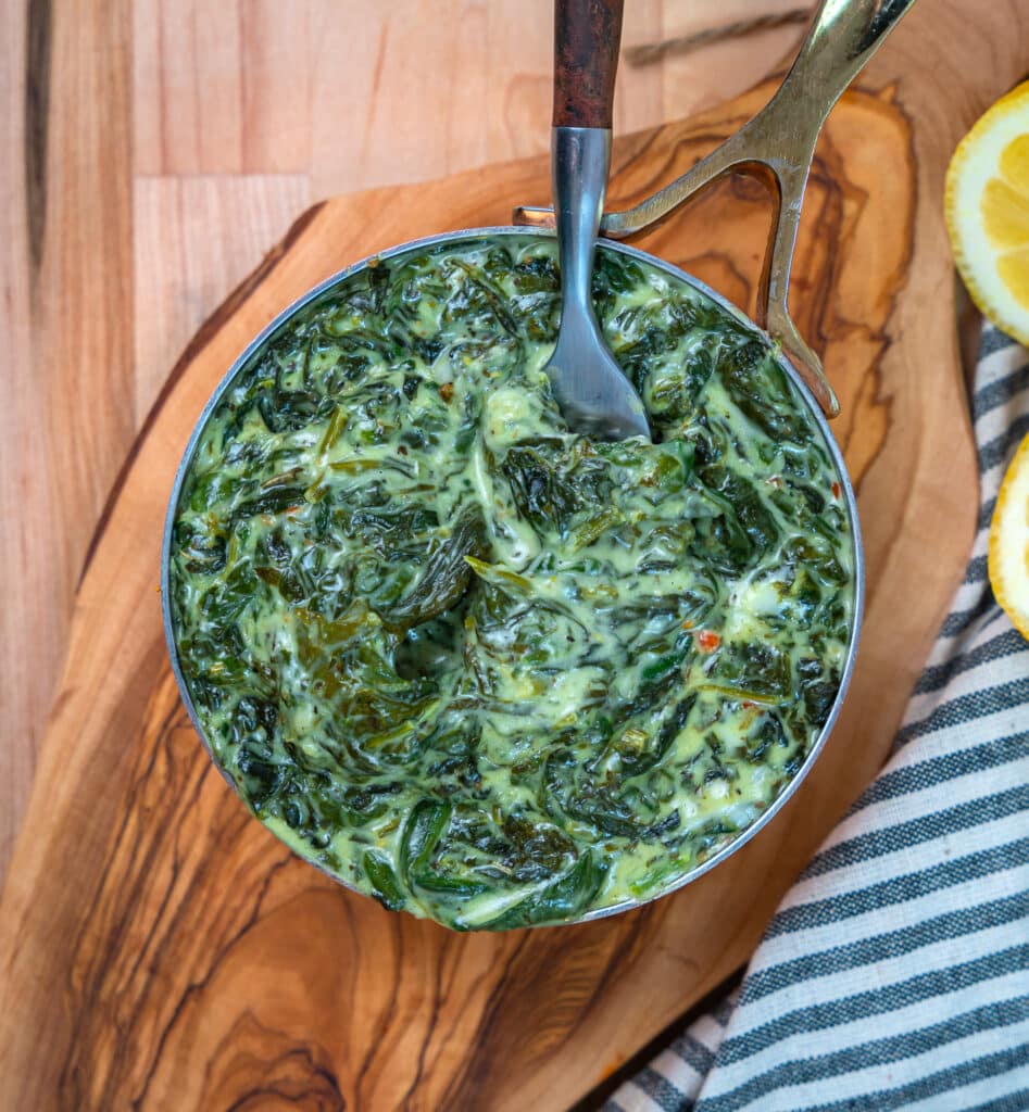 creamed spinach on a cutting board served in a sauté pan