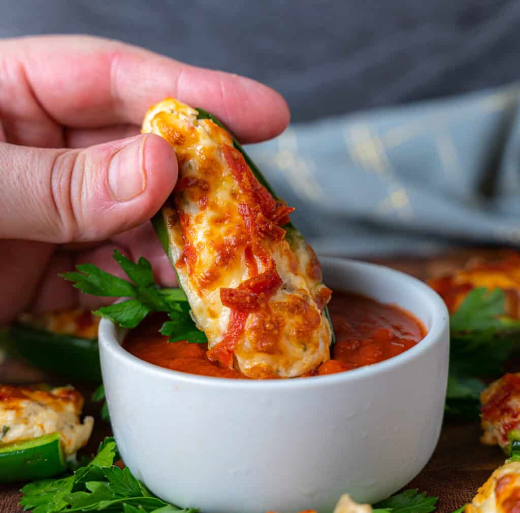 dipping pepperoni pizza keto jalapeño poppers into pizza sauce