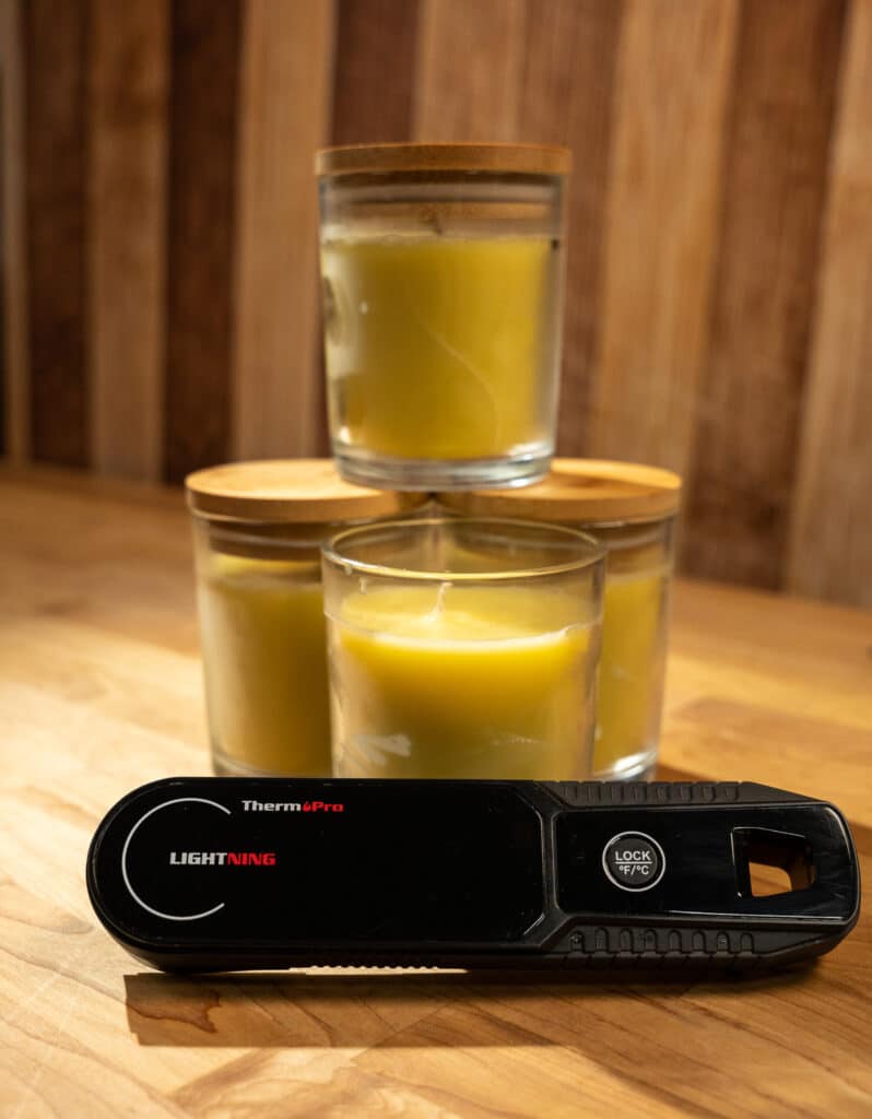 a bunch of finished edible butter candles with an instant read thermometer